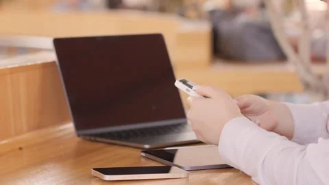 Person is sitting at a table with a laptop and a cell phone Stock Footage 314169376