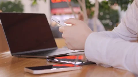 Person is sitting at a table with a laptop and a cell phone Stock Footage 314610022