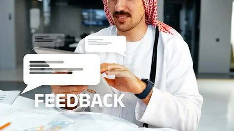 Person sitting at a table looking at a tablet while discussing feedback in a Stock Photos