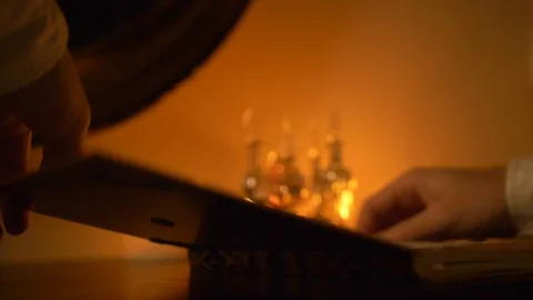 The person sitting at table opens the book with one hand. Light from candles. Stock Footage 105735999
