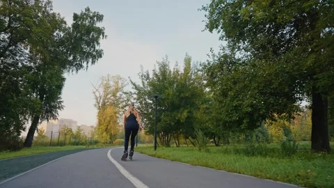 Person skating on a path in a park with trees during late afternoon light Stock Footage 285151887