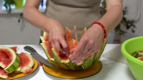 A person skillfully carves a watermelon, creating a decorative pattern with the Stock Footage 336068325
