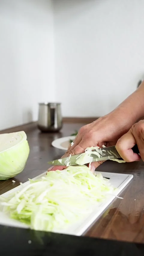A person is skillfully chopping fresh cabbage on a kitchen countertop Video stock 316971845