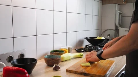 A person skillfully chops fresh vegetables in a bright kitchen. The counter is 動画素材 316480687