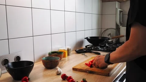 A person skillfully chops red bell peppers on a wooden countertop, surrounded by Vídeos de archivo 316478202