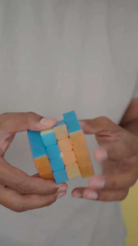 A person skillfully manipulates a vibrant cube puzzle indoors Vidéo 317131234