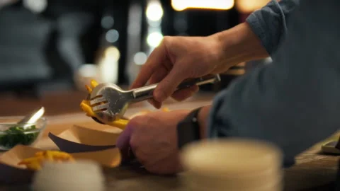 A person is skillfully plating a gourmet dish using tongs in a warmly lit re Stock Footage 323723436