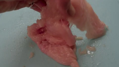 A person skillfully tenderizing a fresh fish fillet on a vibrant blue cutting bo Stock Footage 297202282