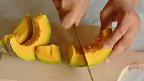 A person slicing clean, seedless raw pumpkin flesh into pieces on a wooden .. Stock Footage 337953079