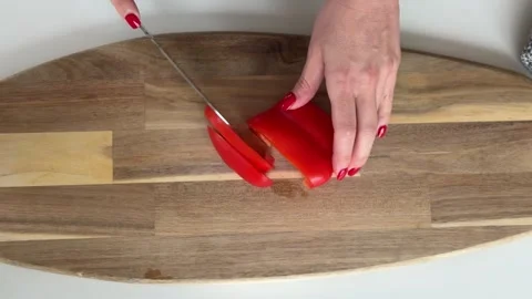 A person slicing red bell pepper on a wooden cutting board Video stock 340526478