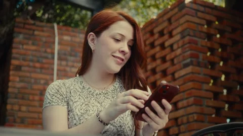 Person smiling while using smartphone outdoors Stock Footage 323928793