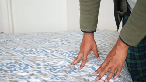 Person smoothing a patterned duvet cover on a bed for a clean look. Stock Footage 332198759