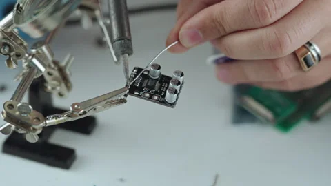 A person soldering diy electronics using a soldering iron and magnifying glass Stock Footage 265561084