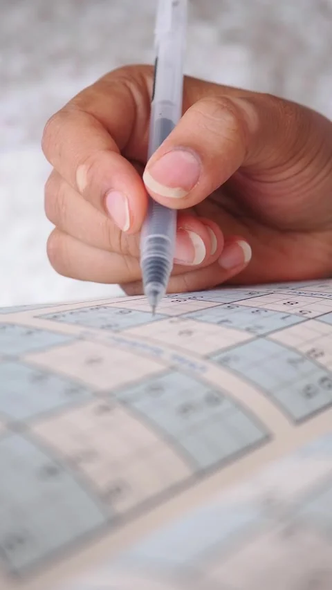 Person Solving a Sudoku Puzzle with a Pen Stock Footage 345014377