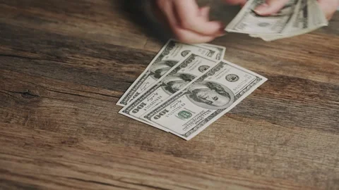 Person Sorting and Counting US Dollar Bills on Rustic Wooden Table Stock Footage 340857218