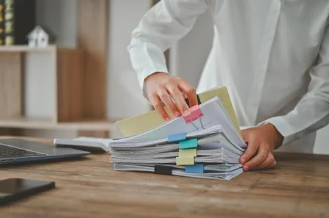 A person is sorting through a stack of papers on a desk Stock Photos