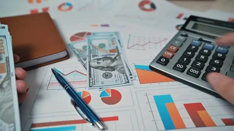A person sorts and counts stacks of cash on a desk with financial documents and Stock Footage 338301492