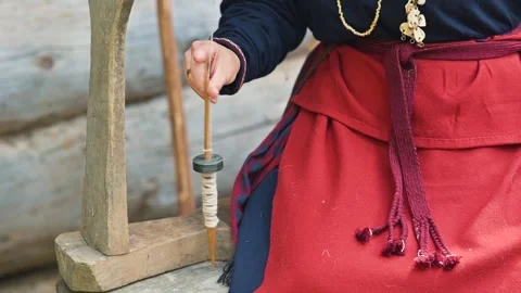 A person spins thread using a drop spindle while dressed in 11th-century Eastern 库存影片 345033790