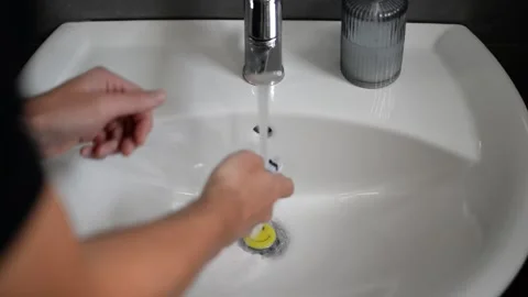 Person spitting tooth paste in white bathroom sink after brushing teeth Stock Footage 204720864