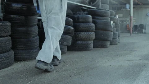 Person spraying a tire storage while wearing protective clothing and a facema Stock Footage 275184710