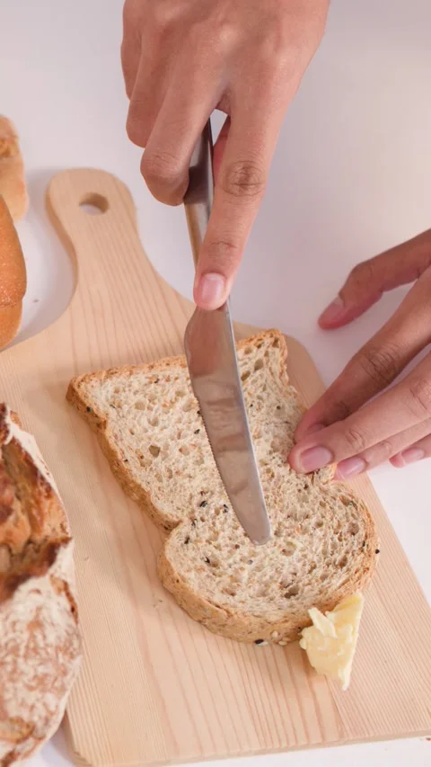 Person Spreading Butter on Multigrain Bread Slice with a Knife Video stock 337748549