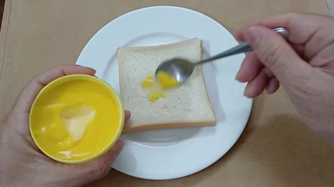 Person spreading butter on slice of bread. Top view of sandwich with butter. 스톡 동영상 260121451