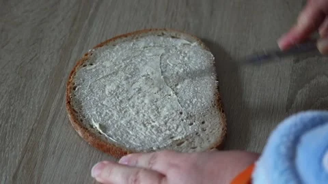 Person spreading butter on a slice of rye bread Stock Footage 334674325