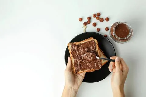 Person spreading chocolate spread on bread slice Stock Photos