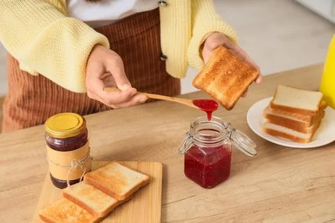 Person spreading jam on toasted bread slice Stock Photos