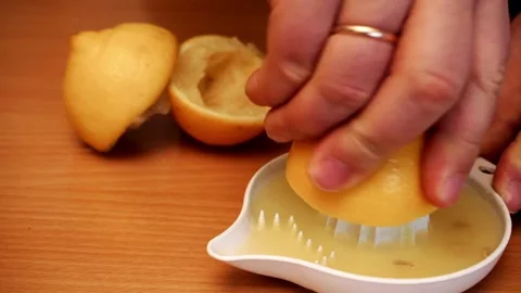 Person squeezes lemon juice with his hands using juicer. fresh juice flows down. Stock-Footage 336588694