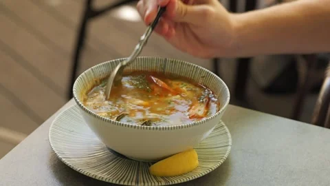 Person squeezing lemon and stirring seafood soup Stock Footage 344966812