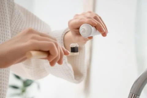 Person squeezing toothpaste onto bamboo toothbrush for daily oral hygiene rou Фото