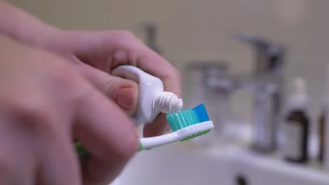 Person squeezing toothpaste on toothbrush, daily dental care for healthy teeth Stock Footage 122497585