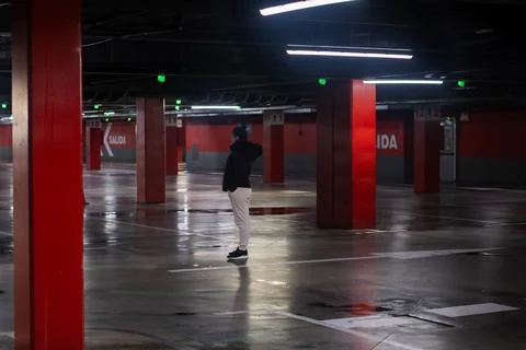 Person standing alone in empty underground parking garage Stock Photos