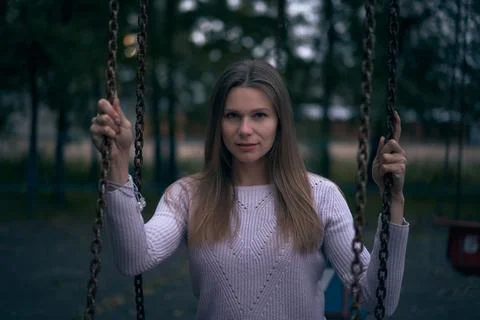 Person standing between swing chains in soft light, creating a calm, intros.. Stock Photos