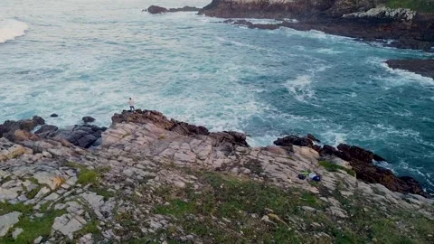 Person Standing On The Edge Of Cliffs Looking On Sea Waves Crashing On Rocks Stock Footage 243299786
