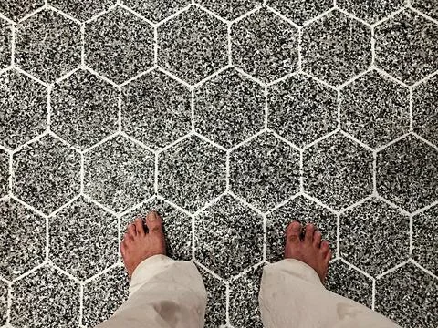 A person standing on a floor with a hexagonal tile pattern Stock Photos