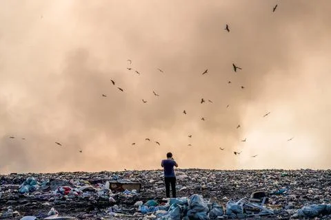 Person standing on a landfill full of garbage and burning garbage piles Stock Photos
