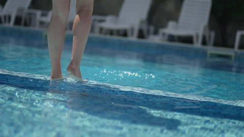 A person is standing in a pool edge and splash water in slow motion. The wate Vidéo 347169014