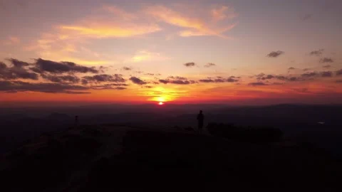 Person standing on rock with epic mountain viewpoint with a sunset drone aerial Stock Footage 201163511