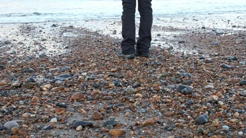 Person standing on the shingle beach as the waves roll in Video stock 253986795