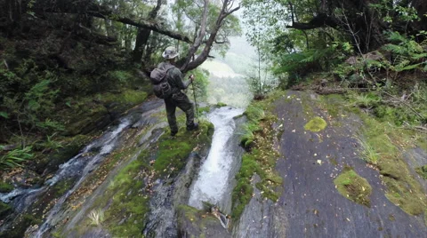 Person standing at top of waterfall with camera travelling past and over falls. Stock Footage 50032279