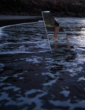 A person is standing in the water with a triangular object, possibly a surfbo Stock Photos