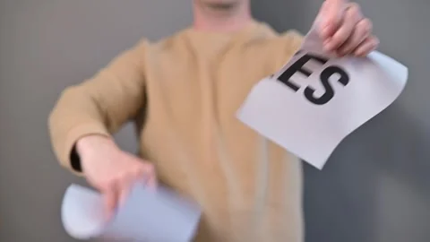 A person stands against a neutral backdrop holding a paper labeled taxes in both 库存影片 338299784