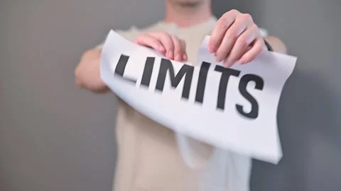 A person stands against a plain background, holding paper signs that display Stock Footage 338299850