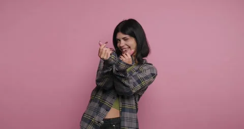 A person stands in front of a pink background. They smile and point a pink .. Видео 326792335