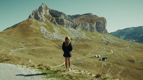 A person stands on a path looking at the mountains of Montenegro with views of Stock Footage 327012116