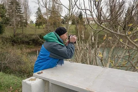 A person stands on a platform capturing views of the river Stock Photos