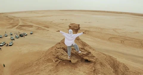 Person stands in triumph spreading hands on rocky Sahara desert cliff with ve Video stock 304666053