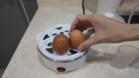 A person steaming two eggs in a modern electric egg cooker 動画素材 322032506